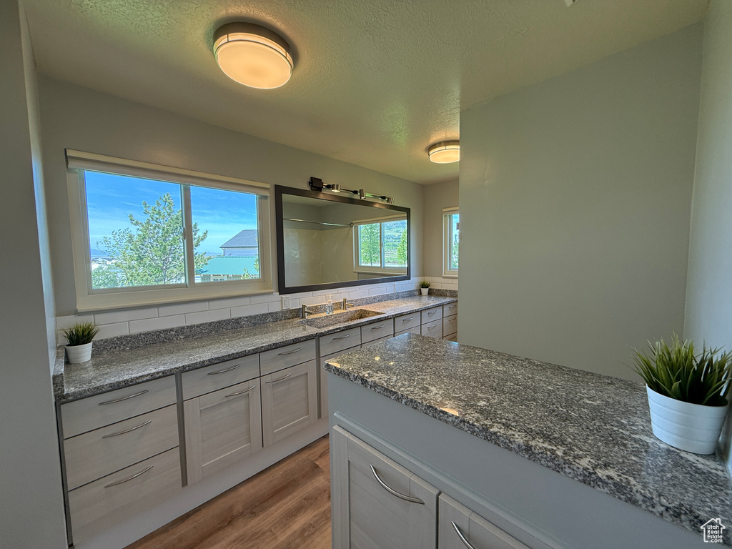 Full bathroom featuring wood finished floors, a textured ceiling, vanity, a shower, and tasteful backsplash
