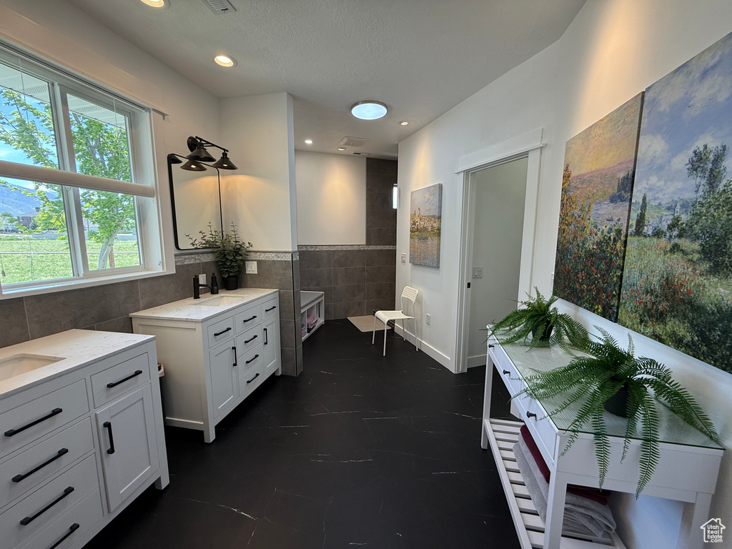 Bathroom with tile walls, two vanities, and recessed lighting