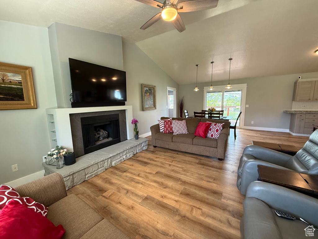 Living area with baseboards, ceiling fan, light wood-type flooring, and lofted ceiling