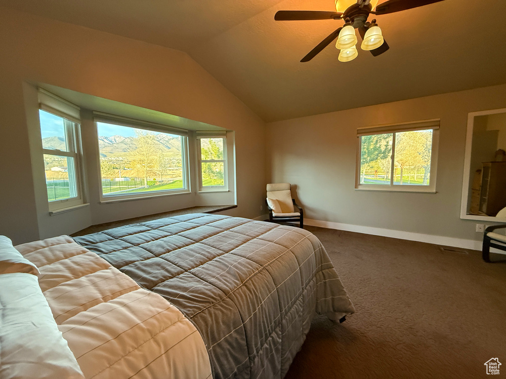 Bedroom with vaulted ceiling, baseboards, carpet flooring, and a ceiling fan