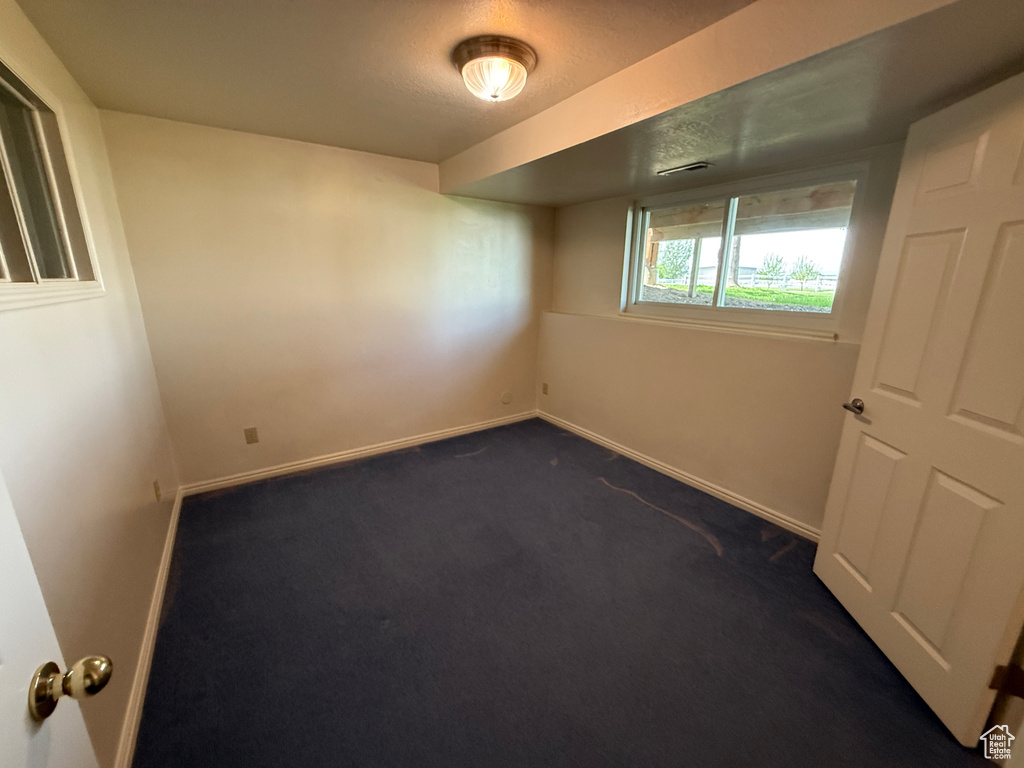 Spare room with dark carpet and baseboards