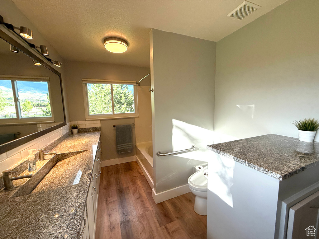 Full bath with wood finished floors, vanity, toilet, shower / tub combination, and decorative backsplash