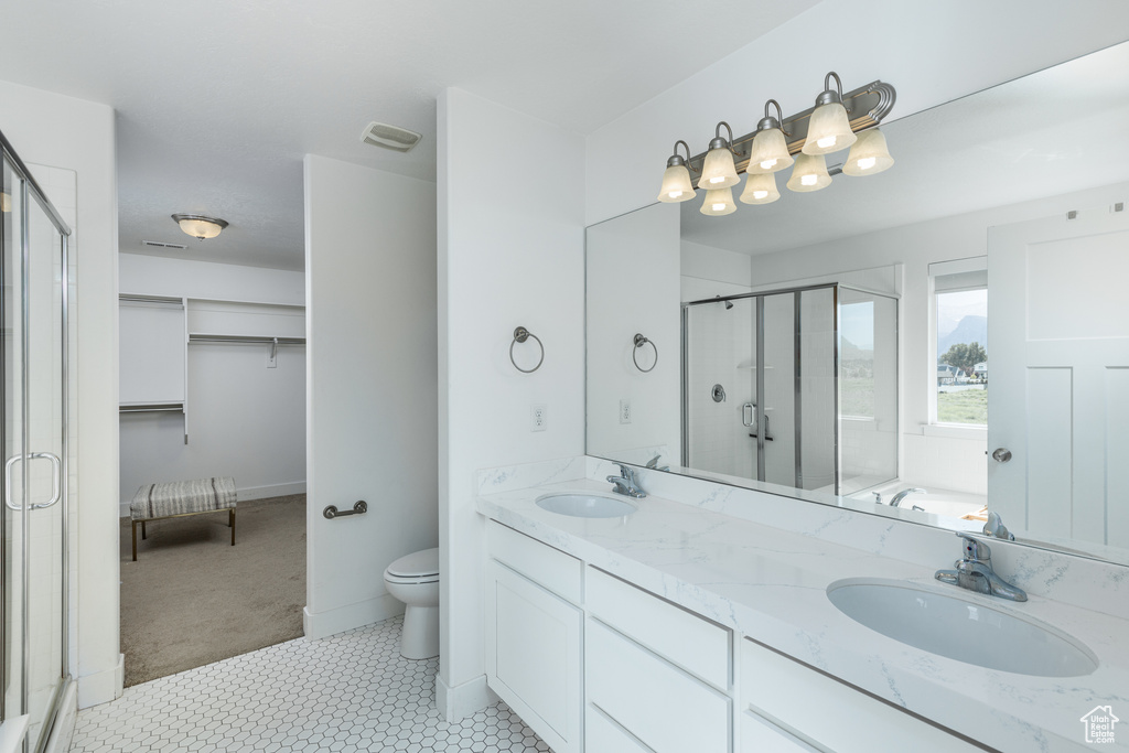 Bathroom with a stall shower, toilet, and double vanity