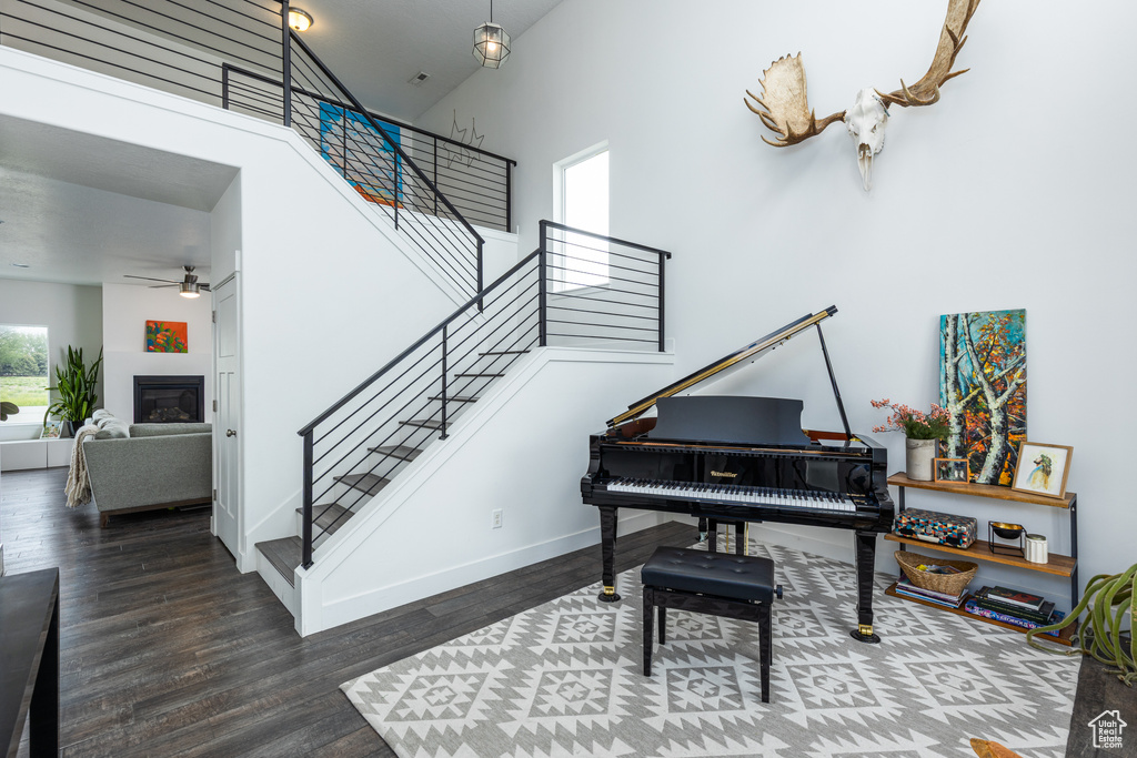 Sitting room with stairs, a ceiling fan, wood finished floors, baseboards, and a high ceiling