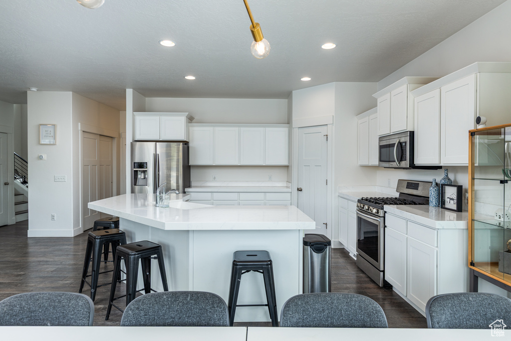 Kitchen featuring appliances with stainless steel finishes, recessed lighting, a kitchen bar, and white cabinetry