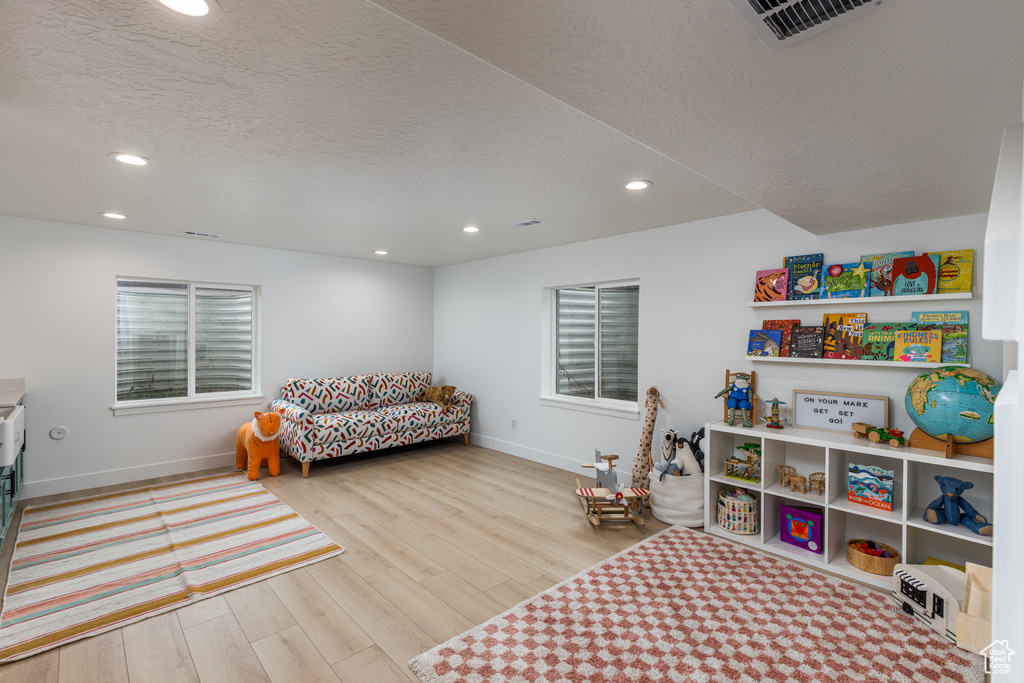 Playroom with recessed lighting, baseboards, wood finished floors, and a textured ceiling