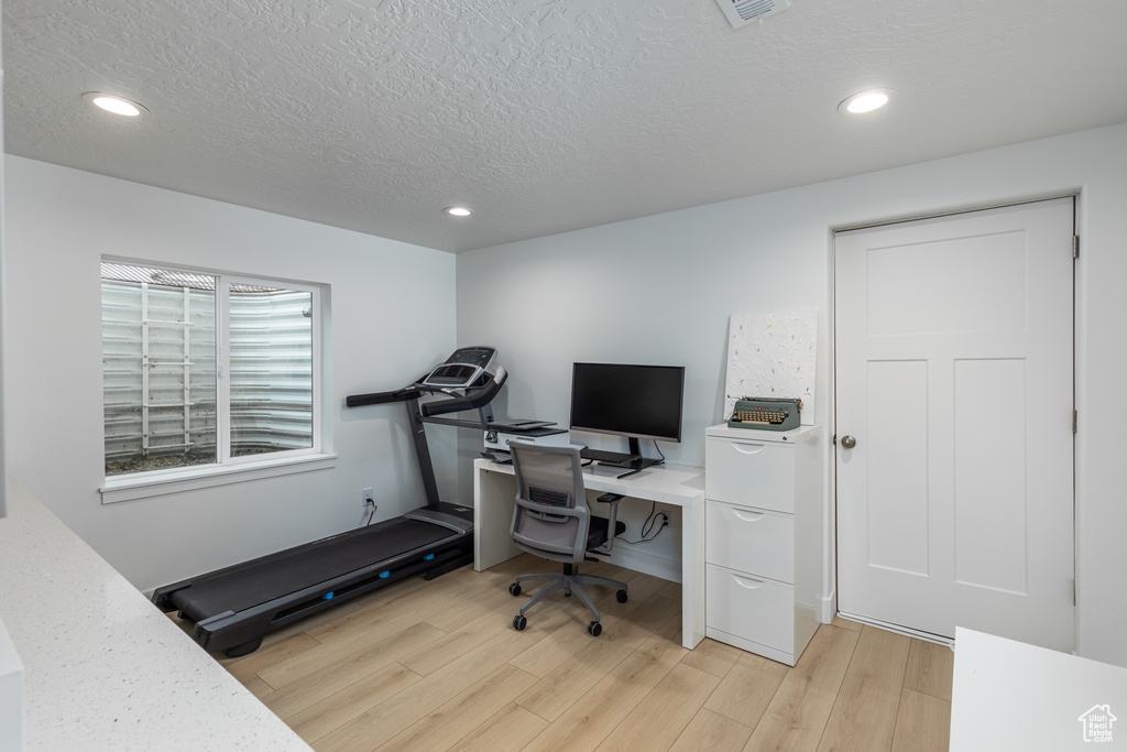 Office space featuring light wood-type flooring, recessed lighting, and a textured ceiling