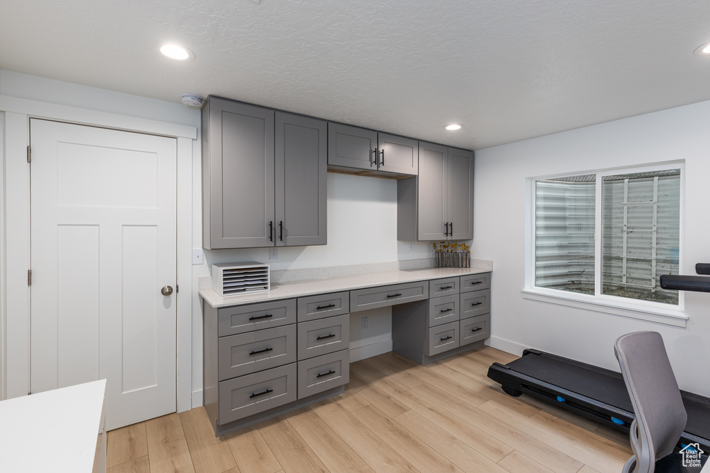 Office space featuring light wood-style flooring, built in desk, and recessed lighting