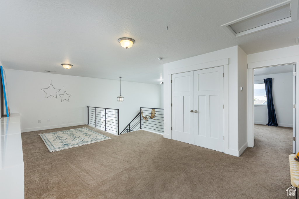 Carpeted empty room with attic access and baseboards