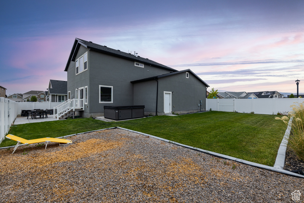 Back of property featuring a hot tub, a patio, and stucco siding