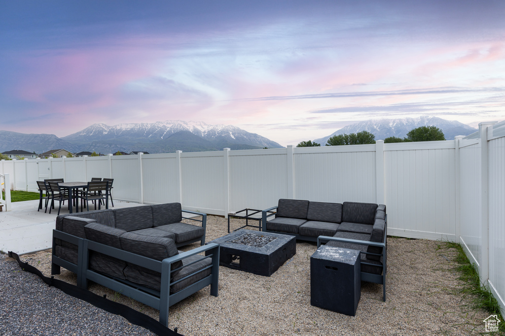 View of patio / terrace with a mountain view, an outdoor living space with a fire pit, and a fenced backyard