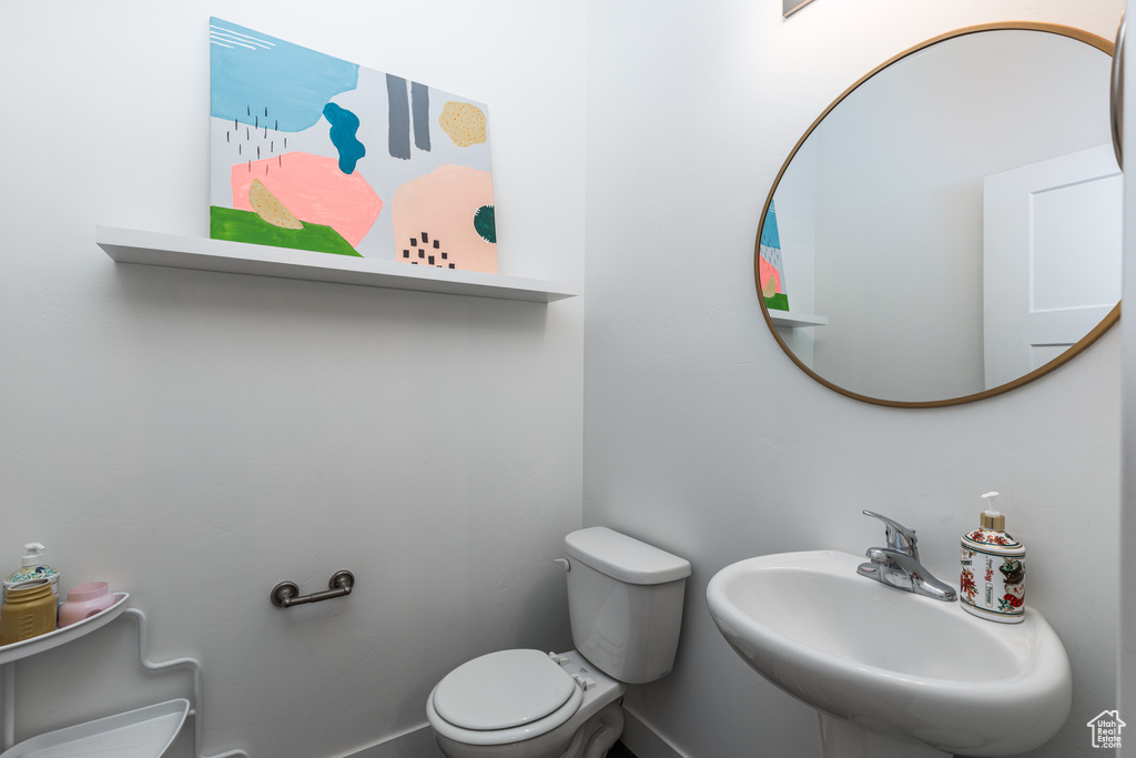 Bathroom featuring a sink, toilet, and baseboards