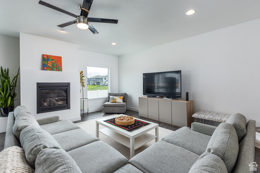 Living area featuring wood finished floors, recessed lighting, ceiling fan, a glass covered fireplace, and baseboards