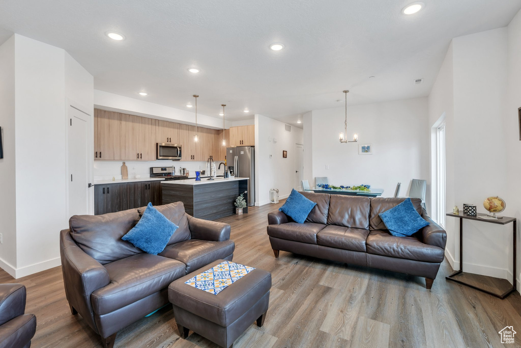 Living room with light wood-style floors, recessed lighting, a chandelier, and baseboards