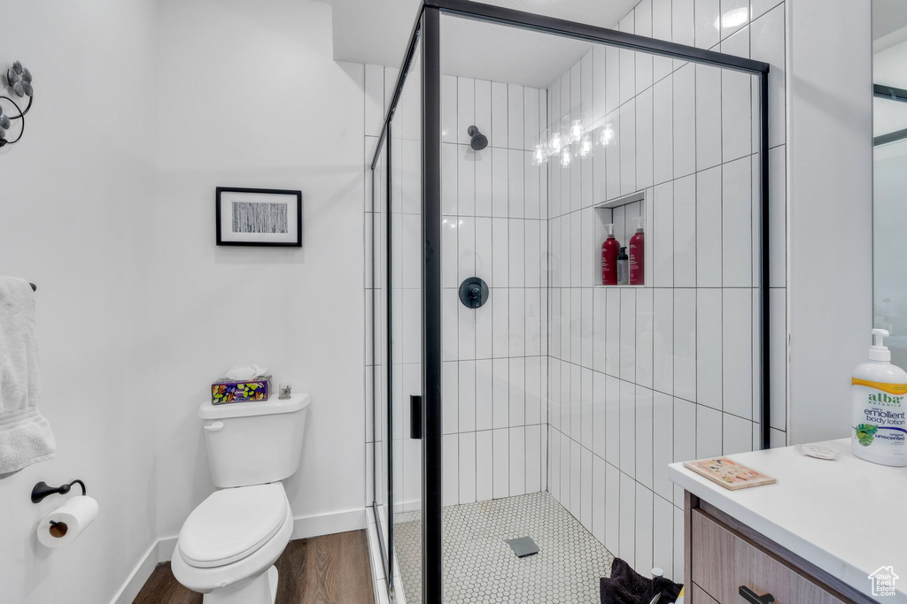 Full bathroom featuring a stall shower, toilet, wood finished floors, and baseboards