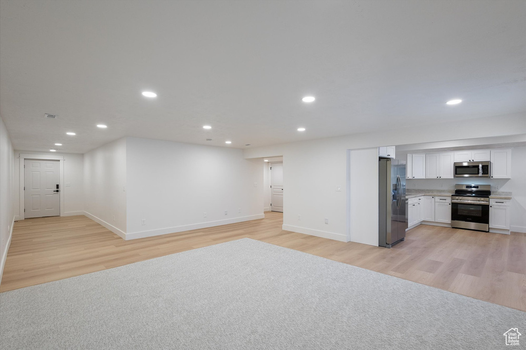 Unfurnished living room featuring light wood finished floors, recessed lighting, and baseboards