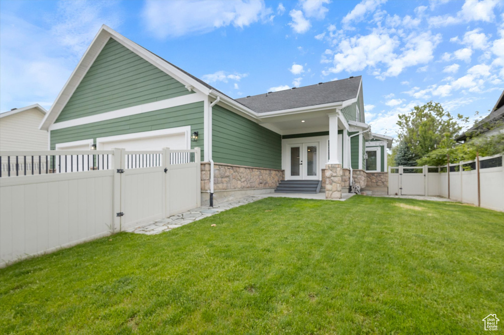 Rear view of house featuring a gate, french doors, and stone siding