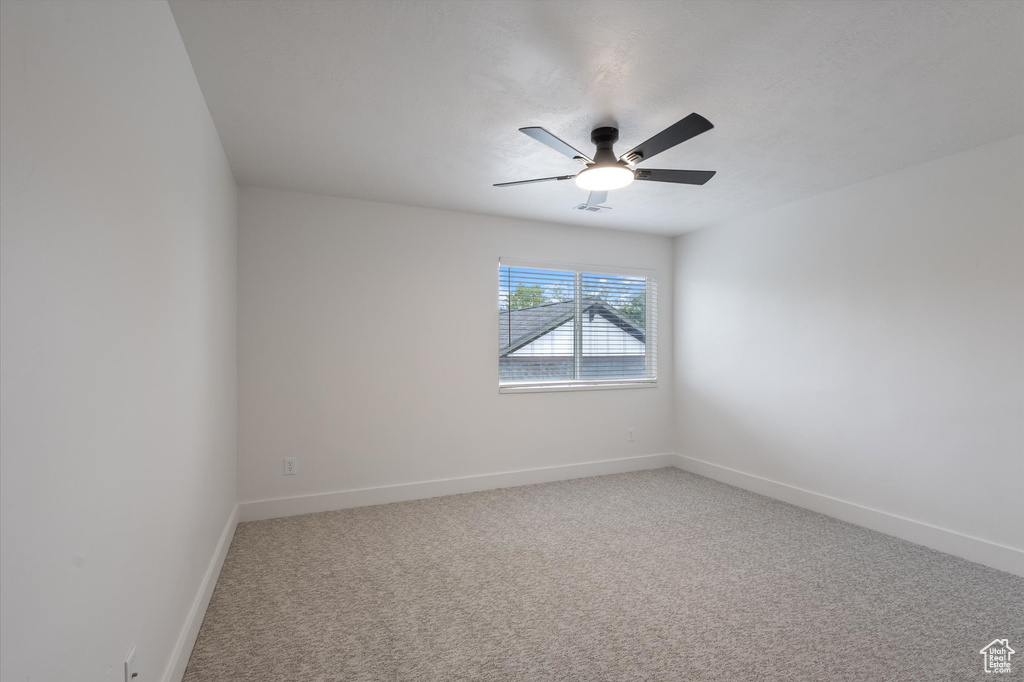 Spare room with ceiling fan, baseboards, and light carpet