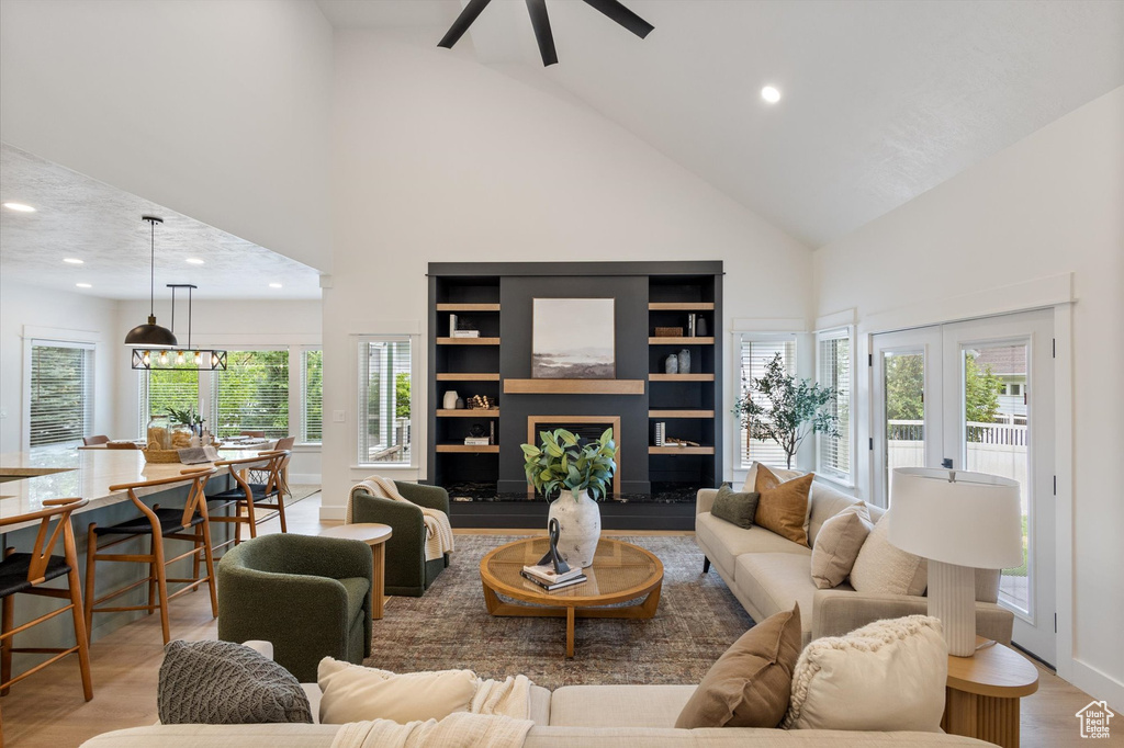 Living area with high vaulted ceiling, recessed lighting, a ceiling fan, french doors, and light wood-style floors