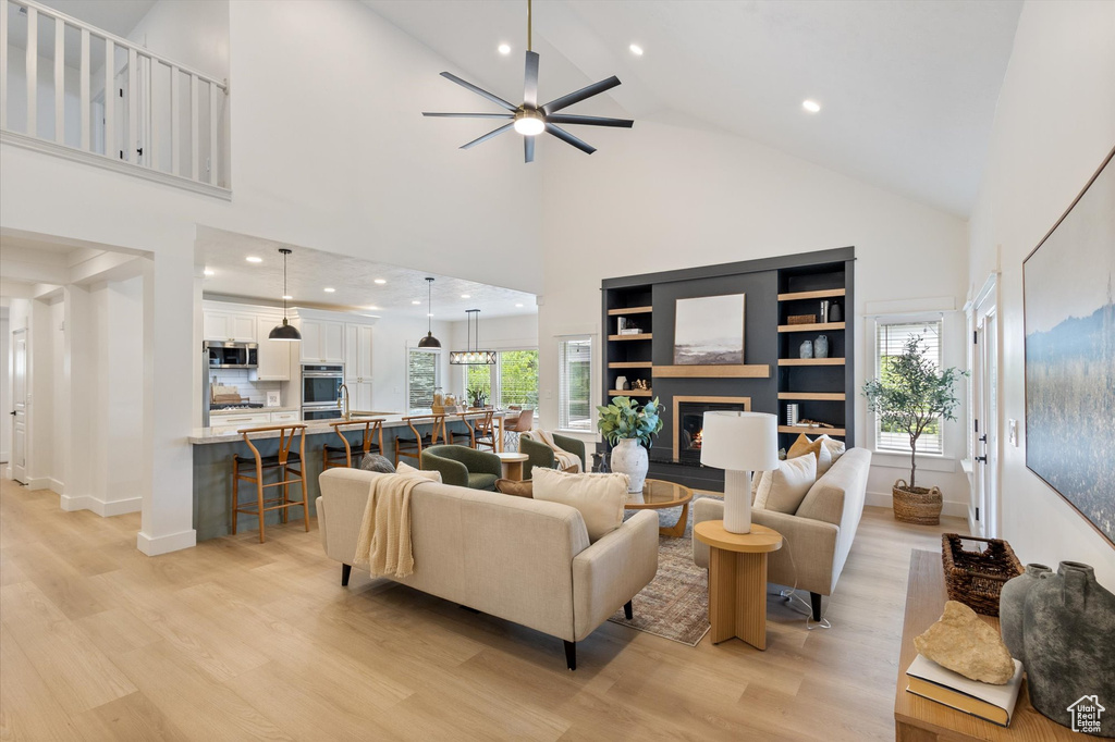 Living area with ceiling fan, light wood-style floors, high vaulted ceiling, healthy amount of natural light, and recessed lighting