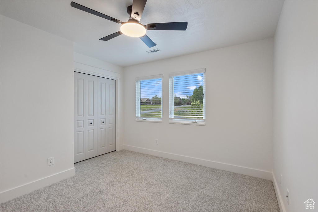 Unfurnished bedroom with carpet, baseboards, a closet, and a ceiling fan