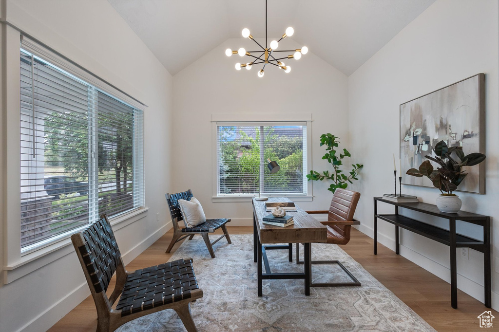 Home office featuring a chandelier, vaulted ceiling, wood finished floors, and baseboards