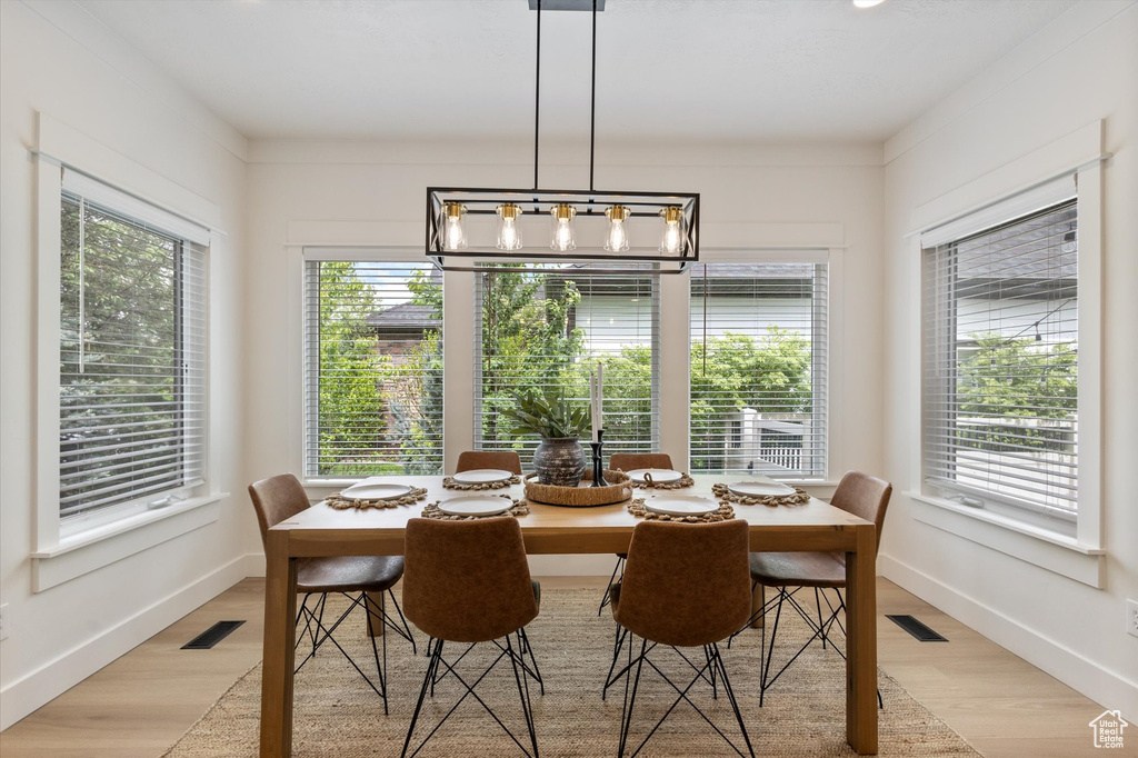 Dining area featuring light wood-type flooring, a chandelier, and baseboards