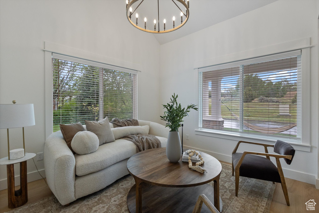Living area with healthy amount of natural light, a chandelier, baseboards, light wood finished floors, and high vaulted ceiling