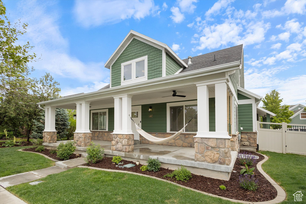 Craftsman inspired home with stone siding, covered porch, a ceiling fan, and a shingled roof
