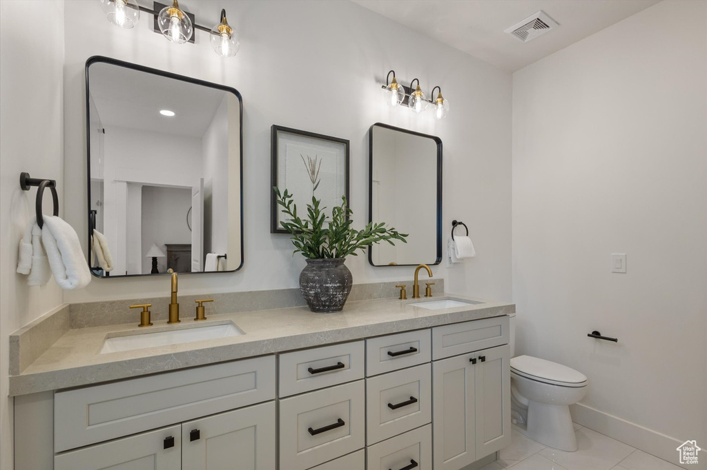 Bathroom featuring double vanity, toilet, and baseboards