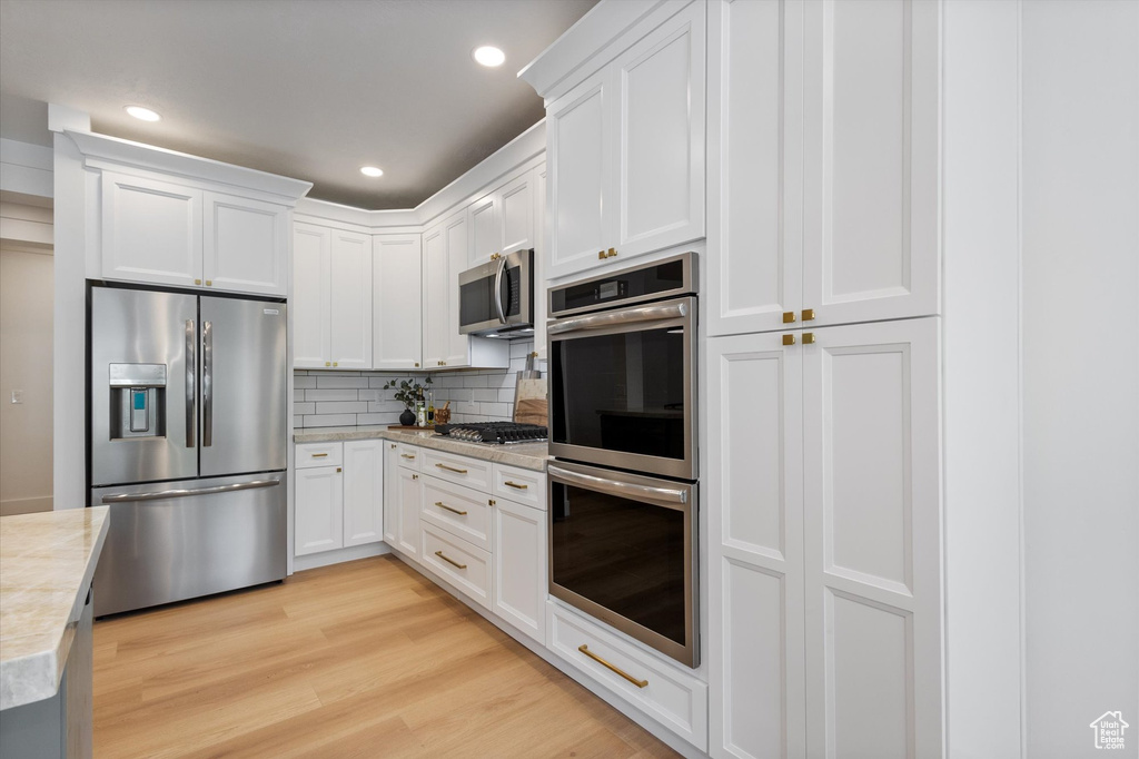 Kitchen with appliances with stainless steel finishes, light countertops, tasteful backsplash, white cabinetry, and recessed lighting