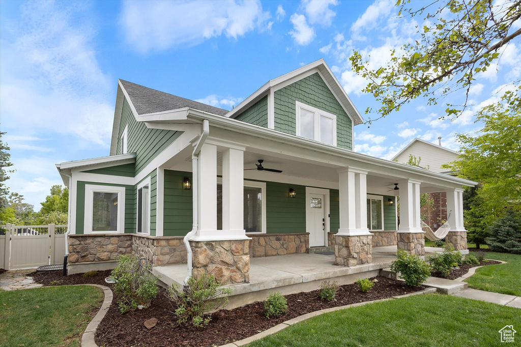 Craftsman-style home with ceiling fan, a porch, stone siding, and roof with shingles