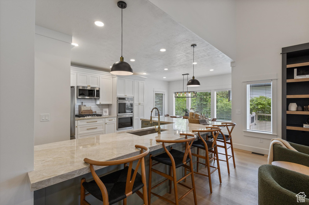 Kitchen featuring a sink, stainless steel appliances, light wood-style floors, white cabinets, and recessed lighting