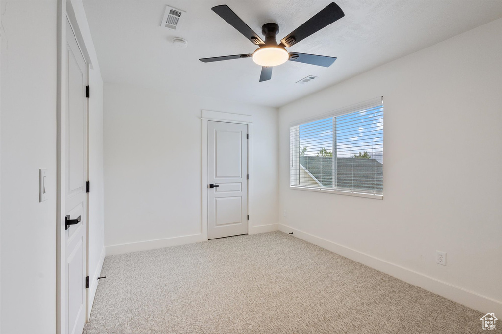 Unfurnished bedroom featuring light carpet, baseboards, and ceiling fan
