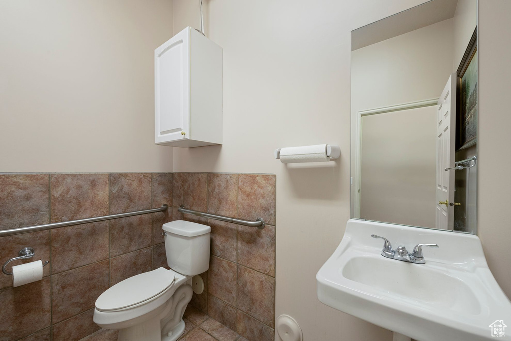 Bathroom with a sink, tile walls, toilet, tile patterned floors, and wainscoting