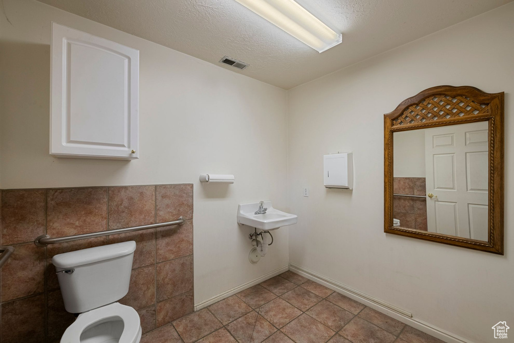 Half bathroom featuring toilet, baseboards, a sink, and tile patterned floors