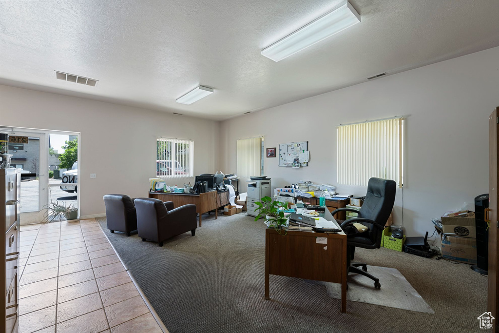 Tiled office space with carpet flooring and a textured ceiling