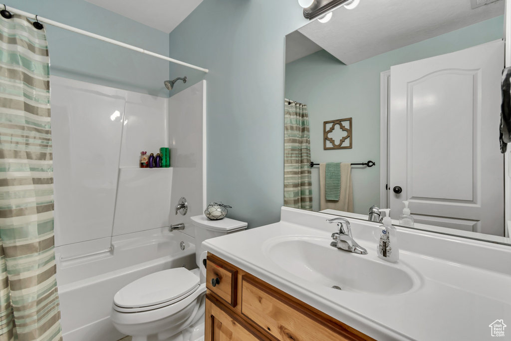 Full bath with toilet, shower / bath combination with curtain, and vanity