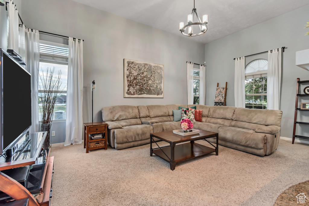 Carpeted living area with a chandelier and baseboards