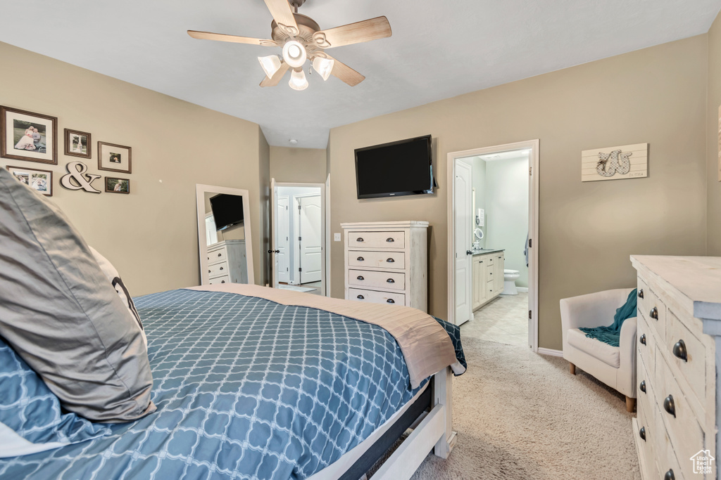 Bedroom with light colored carpet, ceiling fan, ensuite bathroom, and baseboards