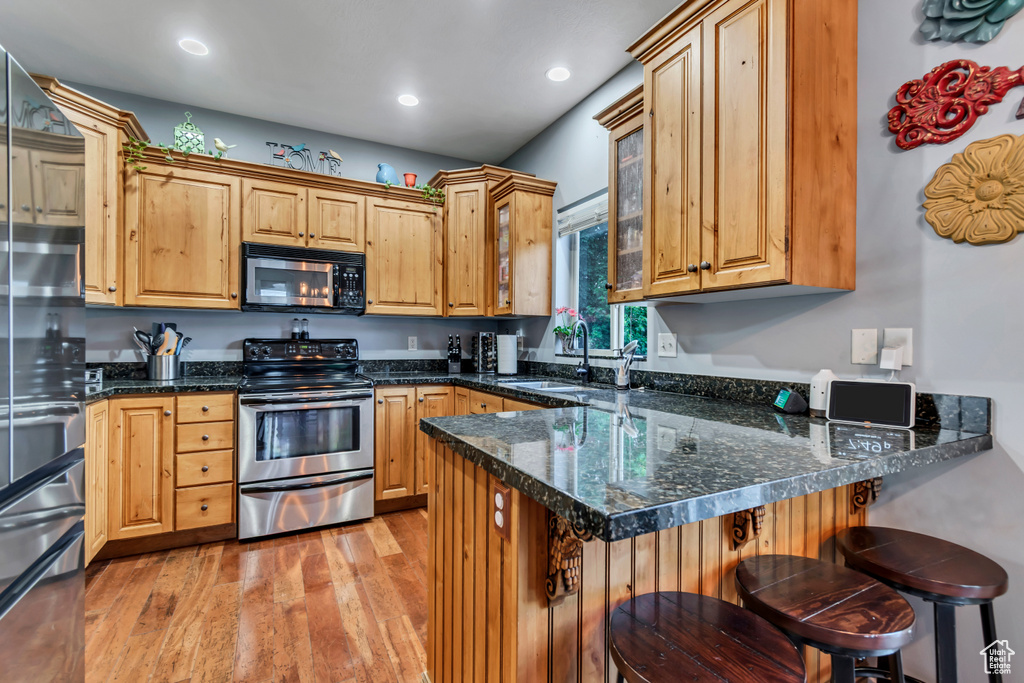 Kitchen featuring stainless steel appliances, a sink, a peninsula, light wood-type flooring, and recessed lighting
