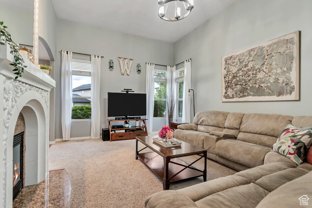 Living area featuring a tiled fireplace, carpet flooring, and a chandelier