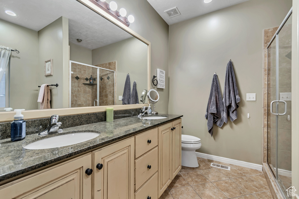 Bathroom with a stall shower, double vanity, tile patterned flooring, toilet, and baseboards