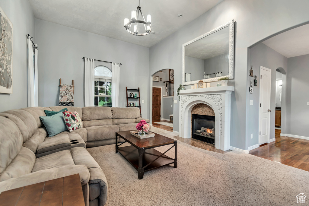 Living room with arched walkways, a chandelier, wood finished floors, baseboards, and a tiled fireplace