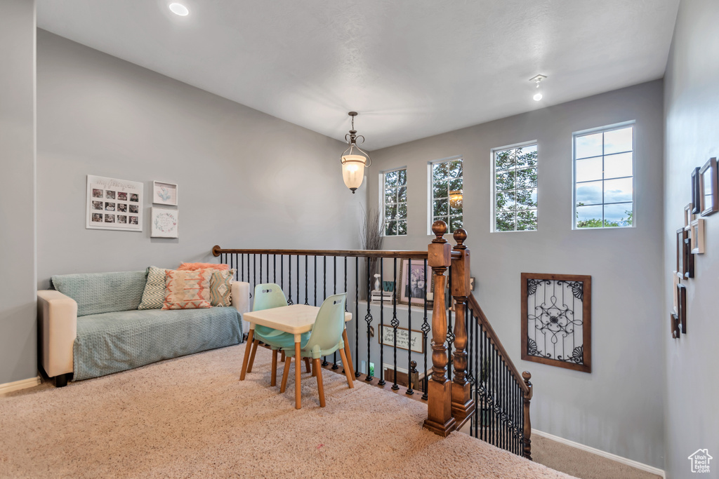 Living area featuring an upstairs landing, baseboards, and carpet