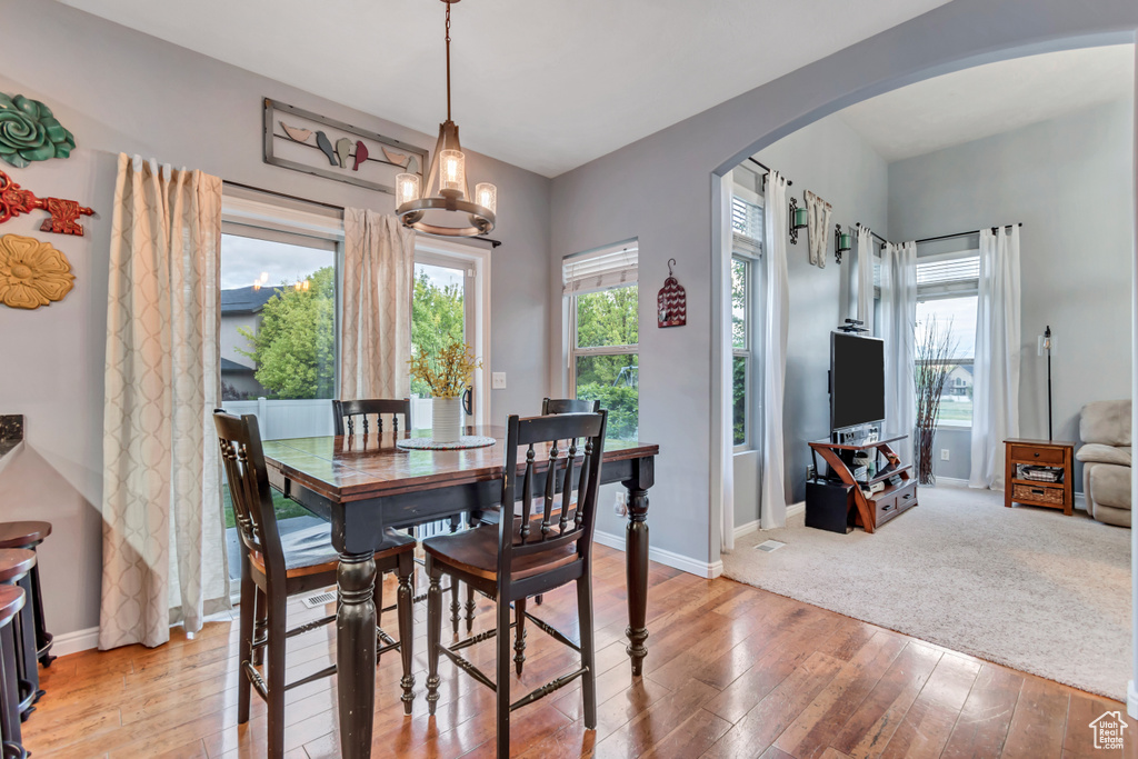 Dining space featuring arched walkways, light wood-style floors, baseboards, and a chandelier