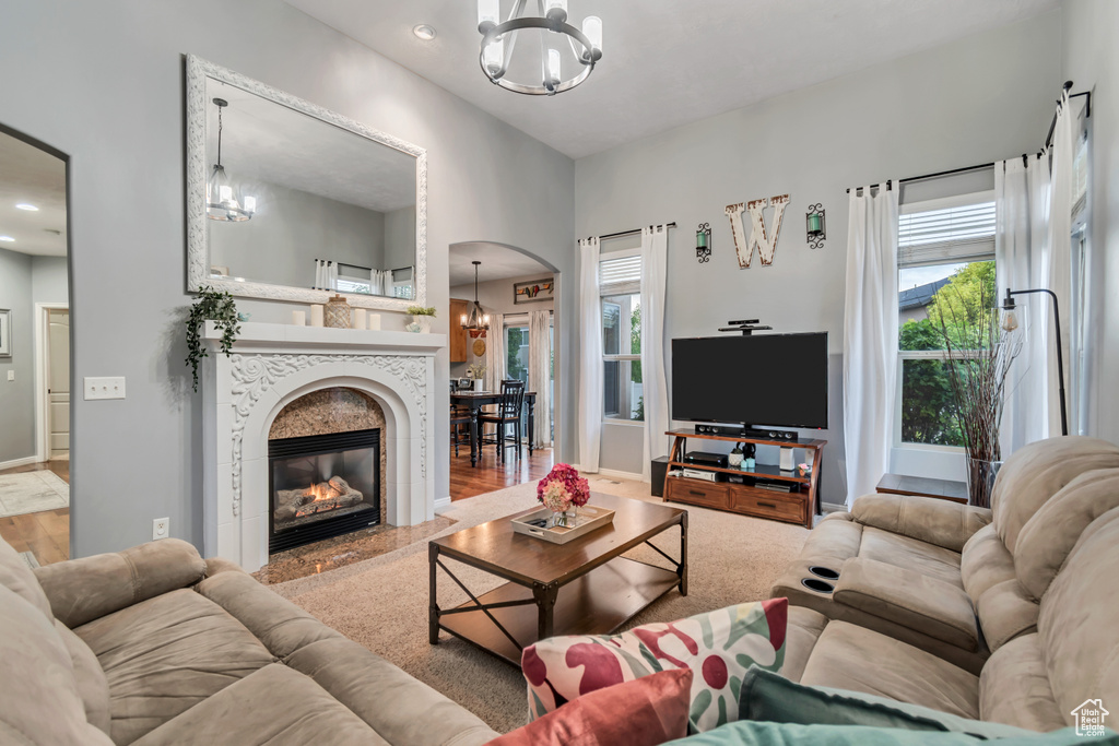 Living room with a chandelier, arched walkways, a tiled fireplace, baseboards, and recessed lighting