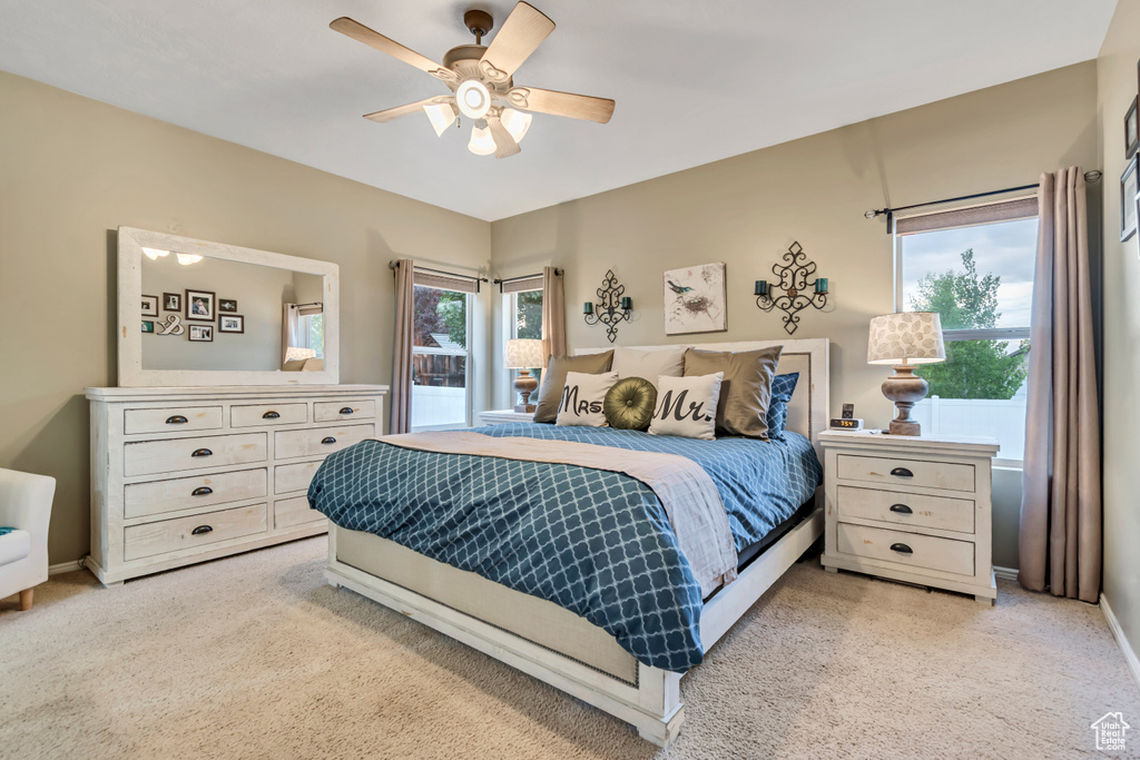 Bedroom with light colored carpet, baseboards, and ceiling fan