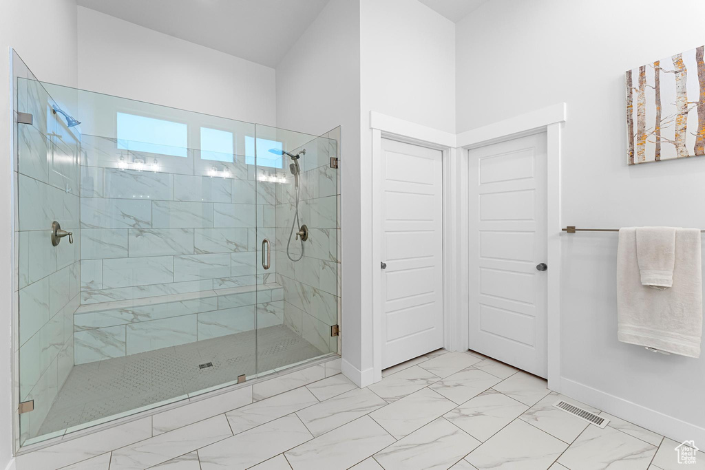 Full bathroom featuring baseboards, marble finish flooring, and a shower stall