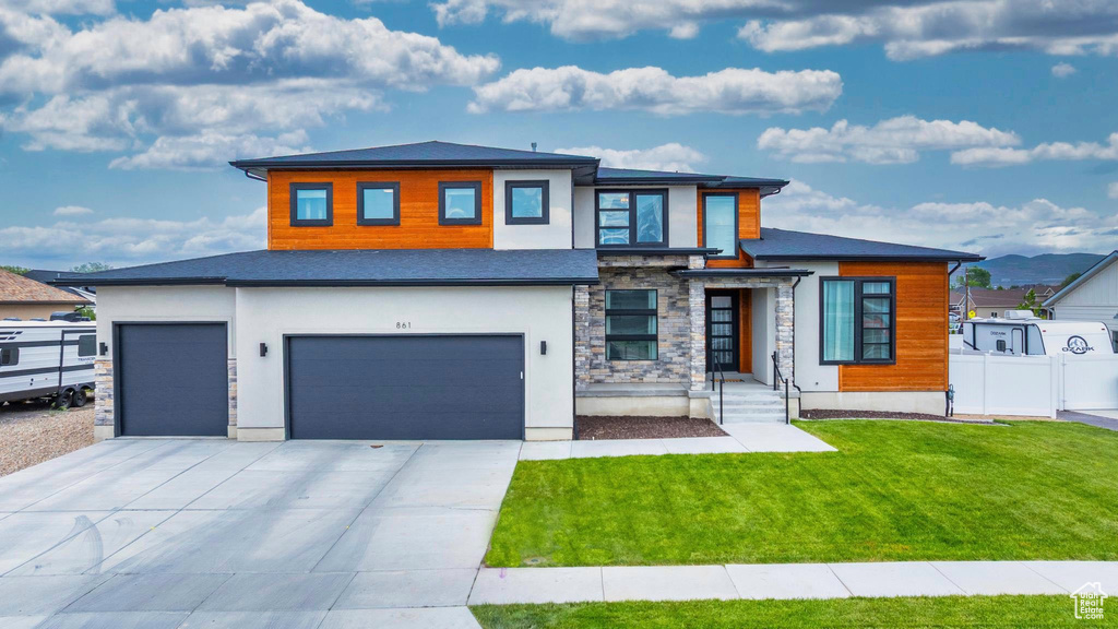 View of front of property with an attached garage, stucco siding, stone siding, and driveway